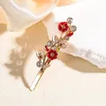 Detail of flower hair clip with red enamel petals, golden leaves and crystal accents - Red