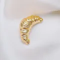 Detailed macro view of the golden croissant brooch with vintage twisted texture on white silk - Gold