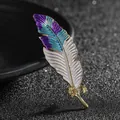 Dettaglio di elegante spilla a piuma dorata con smalto sfumato viola e blu lusso - Blu