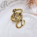 Detail einer goldenen Vintage-Schlangenbrosche mit Schuppen und schwarzen Augen - Antikgold Langer Schlangenstil