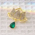 Macro view of a lotus flower brooch featuring emerald green crystal and gold plating - Rhinestone Waterdrop Gem Style (XZ291) / Lotus Waterdrop Green (XZ291)