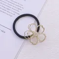 Vue détaillée d'un élastique à cheveux noir avec un charm fleur en perles dorées - Modèle de fleur à quatre pétales en perles artificielles dorées (Élastique à cheveux 23)