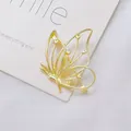 Detailaufnahme der goldenen hohlen Schmetterlingsbrosche mit Herzakzenten auf Seide - Schmetterling Design / Gold