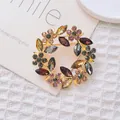 Eleganter goldener Blumenkranz-Brosche mit bunten Strasssteinen auf weißem Texturhintergrund - Mehrfarbige Blume