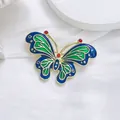 Detail of vintage butterfly brooch with green enamel wings and gold frame on silk fabric - Green