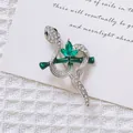 Detalle del broche de serpiente plateado con cristales verdes y pedrería en fondo de tela - Serpiente de Plata Bambú