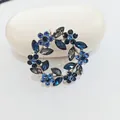Eleganter silberner Blumenkranz-Brosche mit tiefblauen und schwarzen Straßsteinen - Blaue Blume
