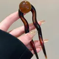 Detail van de U-vormige haarspeld met schildpadpatroon en ronde amberkleurige ronde kraal - Bruin