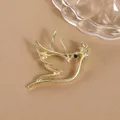 Macro detail of golden dove brooch with olive branch and sparkling black rhinestone eye - Gold