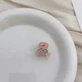 Close-up of a pink bow hair claw clip decorated with rhinestones on a white plate - Pink Bowknot
