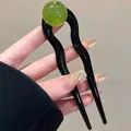 Detailweergave van de U-vormige haarspeld met glanzend zwart golfdesign en groene kraal - Groen