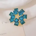Primer plano de broche de flor con cristales azules y montura dorada - Flor Radiante Azul (XZ318)
