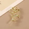 Vue macro d'une broche rose dorée évidée avec texture métallique sur fond neutre - Fleur Creuse / Or