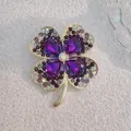 Macro detail of purple crystal clover brooch with golden setting and sparkling zircons - Purple Four-Petal Flower