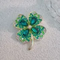 Detail view of crystal four-leaf flower brooch with green stones and gold metal base - Green Four-Petal Flower
