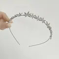 Dettaglio del cerchietto floreale argento con strass AB scintillanti in mano - Fiore a 3 Petali Strass AB