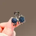 Detailansicht der kleinen dunkelblauen Strass-Schleifen-Haarklammer in der Hand - Schleife-Stil / Blaue Schleife