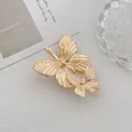 Makro-Detail einer goldenen Doppel-Schmetterling-Haarklammer aus Metall mit Gravur - Doppelter Schmetterling Stil / Gold