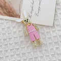 Encantador broche de conejo con strass y peto rosa sobre un fondo de tela de tweed - Conejo Rosa