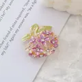 Detail showing purple enamel daisy flowers and green leaves with rhinestones on golden brooch - Hydrangea