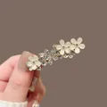 Detail van gouden bloem haarclip met kattenoogstenen en fonkelende steentjes - Gouden Strass Bloem