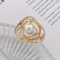 Détail d'une broche artistique dorée aux lignes tourbillonnantes avec une perle blanche - Lignes de Bobinage Irrégulières (Or 5)