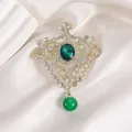 Detailed view of emerald green gemstone brooch with gold hollow crown and hanging bead - Green Crown Style (XZ135)