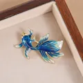Detailed close-up of a blue enamel goldfish brooch with golden scales and fins in a gift box - Blue