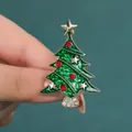 Broche sapin de Noël en émail vert et étoile dorée tenue à la main par un modèle - Noël arbre