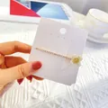 Eleganter goldener Blumen-Haarclip mit Strass und weißen Blüten auf Displaykarte - Einzelne Blume Strass Haarnadel Stil