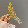 Dettaglio macro della molletta ad ali d'angelo con strass gialli e fiocco elegante - Spiga di grano