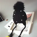 Black knit baby beanie with fur pom-pom, pearls, and earflaps on a white frame - Black