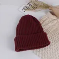 Flat lay of dark red ribbed knit baby beanie with warm texture and aesthetic props - Burgundy