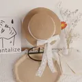 Kids straw sun hat featuring a delicate white lace ribbon bow on a display stand - 50 / Khaki