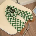 Grün-weiß karierter Strickschal für Kinder mit braunem Rippsaum auf einem Stuhl - Grün Farbblock Gitter