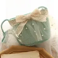 Light green woven straw crossbody bag featuring creamy lace bow and white pearl accents - Lake Blue