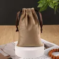 Brown velvet drawstring pouch with satin ribbon on a white pedestal display - Khaki