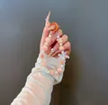 Dettaglio portachiavi con perline, fiocco arancione e quadrifoglio tenuto in mano - Ciondolo di perline con fiocco (B-246) / Arancione
