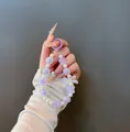 Detail of beaded phone charm with purple petals, pearls, and a large bow decoration - Bow Beaded Charm (B-246) / Purple