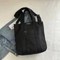 Versatile black canvas tote bag with adjustable strap and front zipper pocket - Black