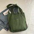 Army green canvas tote bag with adjustable shoulder strap and front zipper pocket - Green