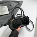 Chic black patent leather rectangular handbag with gold hardware and dual handles - Black