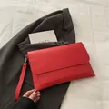 Detail of red PU leather envelope clutch bag showing smooth texture and removable wrist strap - Red