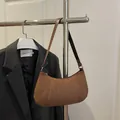Bolso baguette retro de ante marrón con correa de cuero en un soporte plateado - café