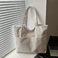 Borsa tote minimalista in velluto a coste beige con doppie tasche frontali su tavolo - Bianco
