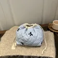 Quilted light blue drawstring pouch featuring black embroidered bows and minimalist design - Blue