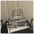 Detail of silver metallic Boston bag featuring a pearl bow charm on a fashion magazine - Silver