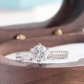 Close-up of a classic six-prong round moissanite ring set in a wooden jewelry box - HK Size 9 / 1 ct