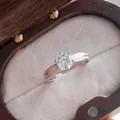 Detail of six-prong moissanite ring with two-tone band on velvet jewelry box - HK Size 9 / 3 ct