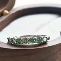 Close-up of seven round-cut green moissanite stones set in a silver eternity ring - US 5 / Teal
